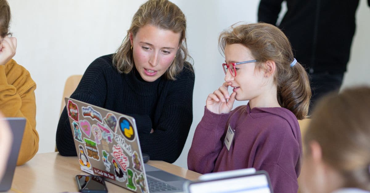 Eine junge Frau erklärt einem Mädchen etwas auf einem Laptop